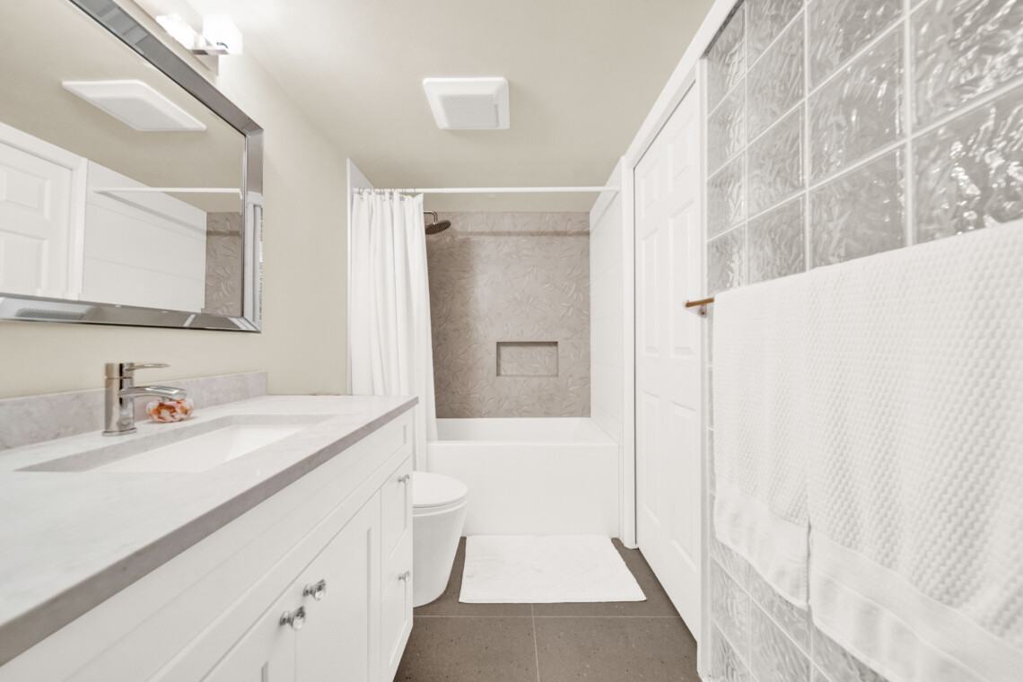 Bathroom interior with white vanity, marble countertop, and large rectangular mirror above the sink