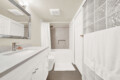 Bathroom interior with white vanity, marble countertop, and large rectangular mirror above the sink