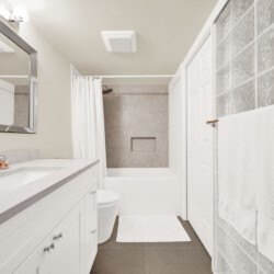 Bathroom interior with white vanity, marble countertop, and large rectangular mirror above the sink