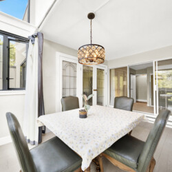 Sunlit indoor dining area with a daisies-pattern tablecloth, glass doors, and a decorative chandelier.