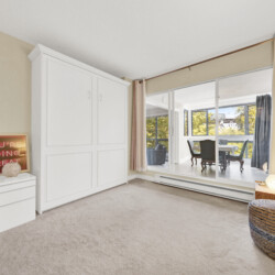 Bright living room with a white built-in wardrobe, beige walls, and a large window with pink curtains.