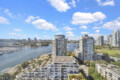 City skyline with modern high-rise buildings along a marina under a blue sky with scattered clouds.