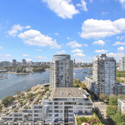City skyline with modern high-rise buildings along a marina under a blue sky with scattered clouds.
