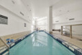 Indoor, empty swimming pool with tiled pools and lane markers; signs warn no diving, water calm and pale light from skylights above