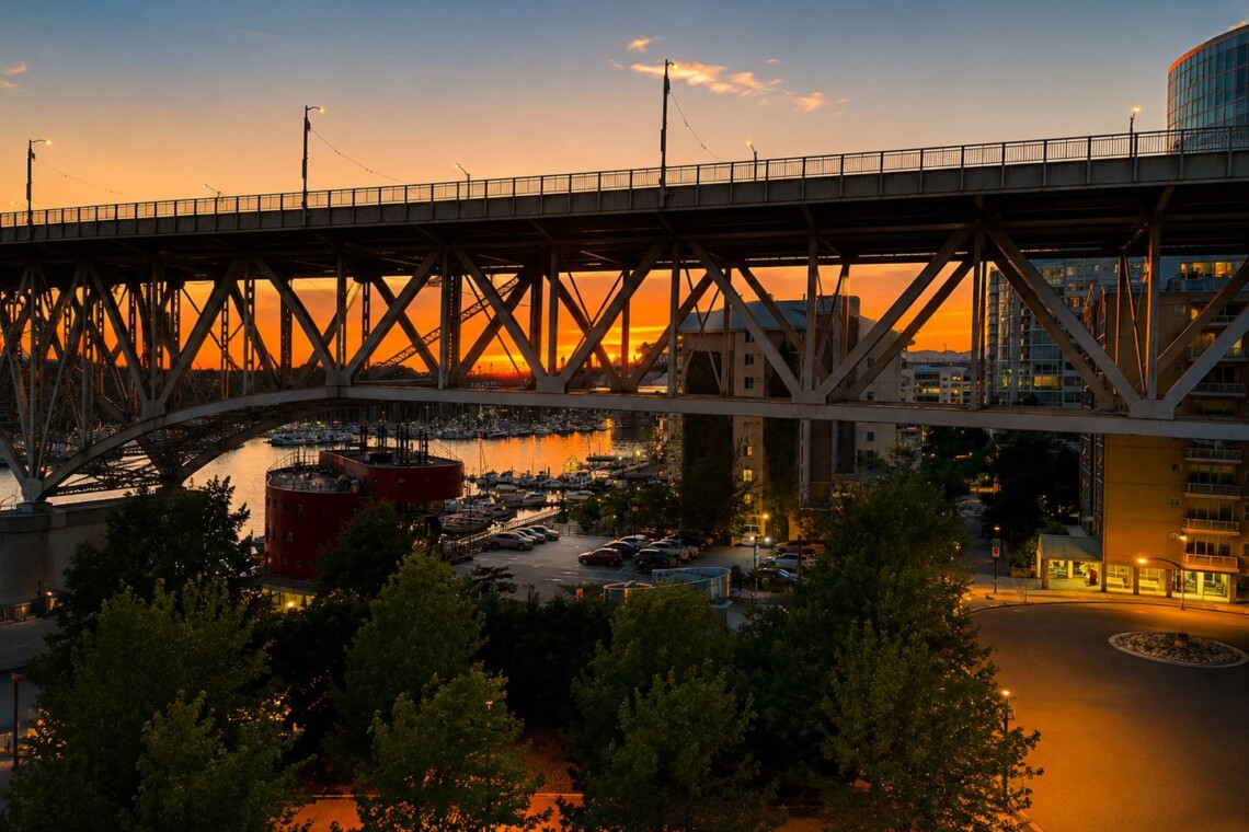 Sunset over a large metal bridge spanning a marina with yachts and orange sky in the background, city buildings on the right.