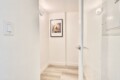 Narrow white hallway with a framed dog portrait on the far wall.
