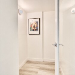 Narrow white hallway with a framed dog portrait on the far wall.