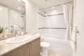 Modern bathroom: beige vanity with oval sink, large mirror, and soap dispenser nearby.