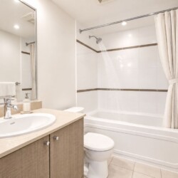 Modern bathroom: beige vanity with oval sink, large mirror, and soap dispenser nearby.