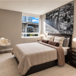 Contemporary bedroom with a dark wood platform bed, beige bedding, and a large black-and-white cityscape photograph above the headboard.