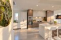 Modern kitchen with white and wood cabinets, stainless steel appliances, and a white island with bar stools under warm lighting.