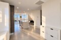 Bright, modern kitchen with a central island, white cabinetry, and bar seating, opening to a living area with city skyline views amid natural light.