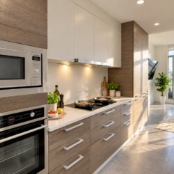 Modern kitchen with stainless-steel microwave and oven, white upper cabinets and wood-toned lower cabinets; sunlit balcony visible in the background.