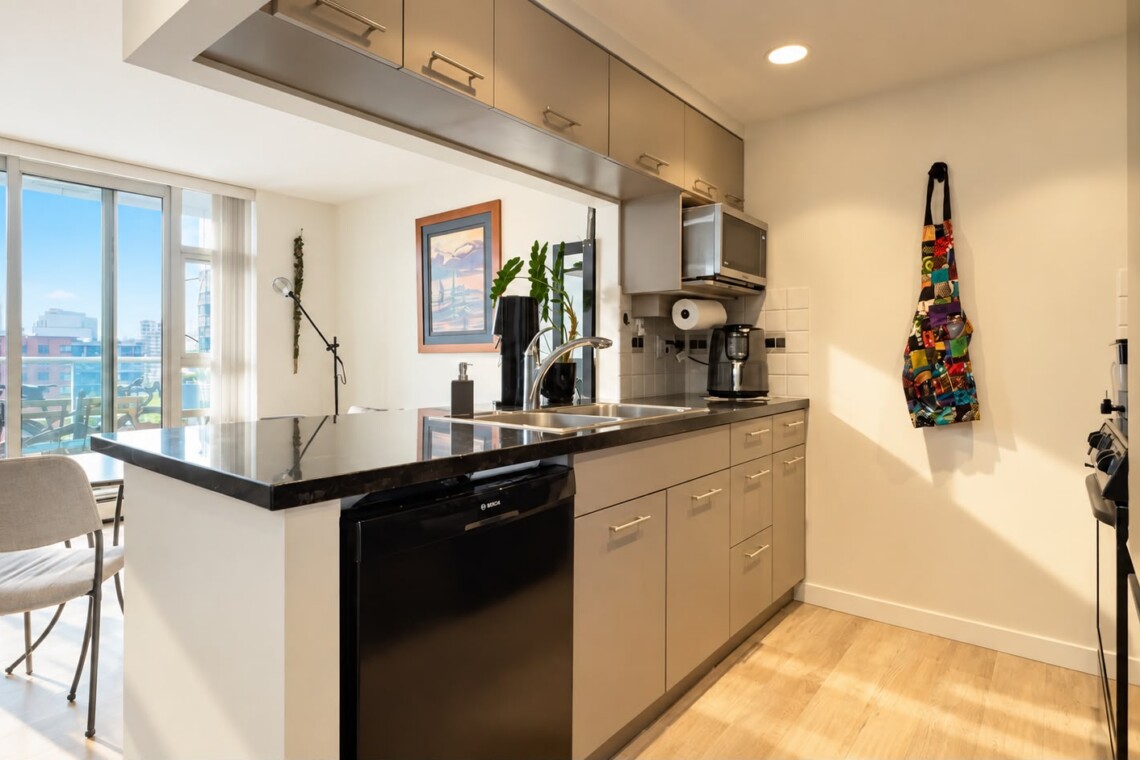 Modern kitchen with an island, black granite countertop, double sink, and stainless appliances; balcony view outside window.