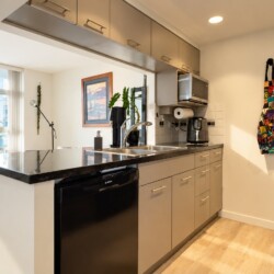 Modern kitchen with an island, black granite countertop, double sink, and stainless appliances; balcony view outside window.
