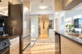 Open-concept kitchen with stainless steel refrigerator, stove, and island; warm sunlight casts shadows across the space.