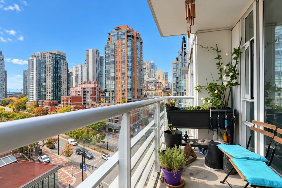 Balcony with blue lounge chair, potted plants, and urban city skyline of tall glass buildings across the street on a sunny day