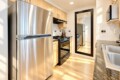 Modern kitchen with stainless steel refrigerator, gas range, and microwave, light wood cabinets, and granite countertops.