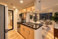 Open-concept kitchen with a black countertop island, stainless steel appliances, and a living area with city-view windows in the background.