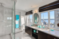 Modern bathroom with double sinks, black cabinets, and a wide window view of the city and water.