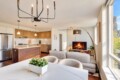 Open-concept living space with a wooden-kitchen island, stainless steel appliances, and a gray sofa facing a fireplace TV.