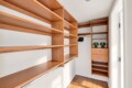 Walk-in closet with warm wooden shelving, a hanging rod, and a tall drawer cabinet; two green lamps on the shelf.