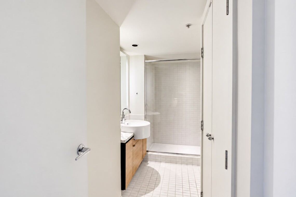 Modern bathroom with a white vessel sink on a wooden vanity and a glass shower enclosure.
