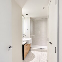 Modern bathroom with a white vessel sink on a wooden vanity and a glass shower enclosure.