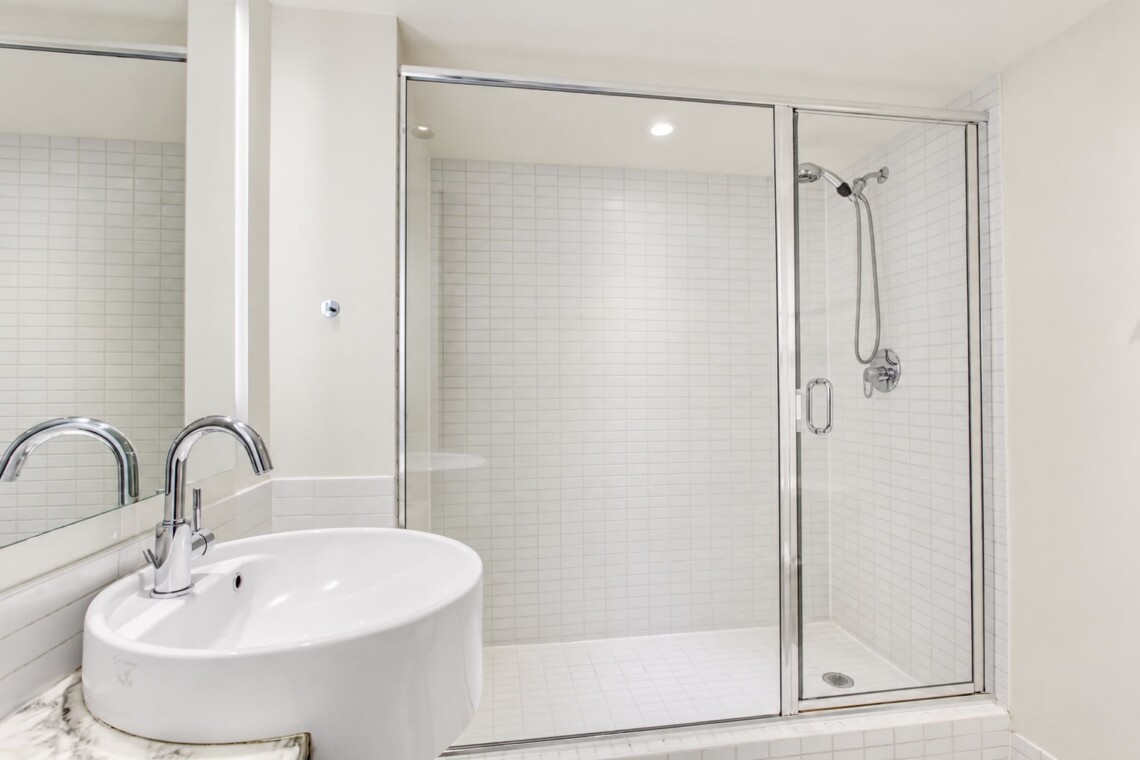 Modern bathroom with a glass-walled shower and a white ceramic sink with a chrome faucet.
