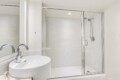 Modern bathroom with a glass-walled shower and a white ceramic sink with a chrome faucet.