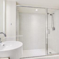 Modern bathroom with a glass-walled shower and a white ceramic sink with a chrome faucet.