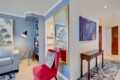 Cozy living area with blue walls, gray sofa, black floor lamp, a red accent chair, and a gold-framed mirror.
