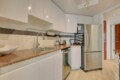 Modern kitchen with white cabinets, brown granite countertops, and a stainless steel refrigerator and dishwasher.