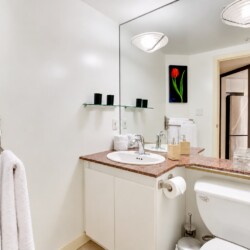 Modern bathroom with white vanity, marble countertop, and large mirror reflecting a towel rack and tulip artwork above the sink area.